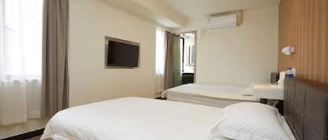 A hotel room with two beds, a flat-screen TV, an air conditioning unit, and a window with curtains.