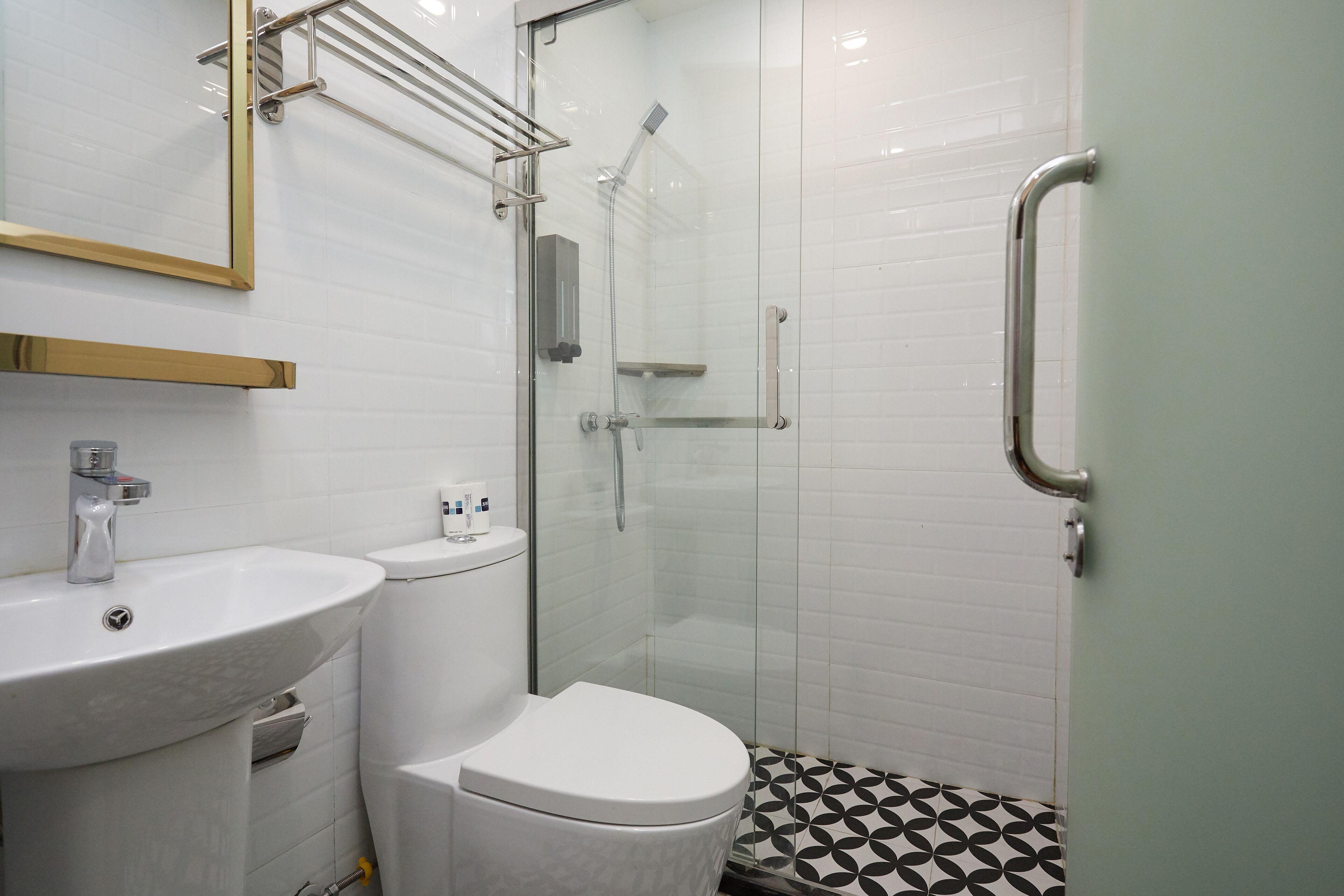 A bathroom with a white sink, toilet, and a glass-enclosed shower area with a handrail.