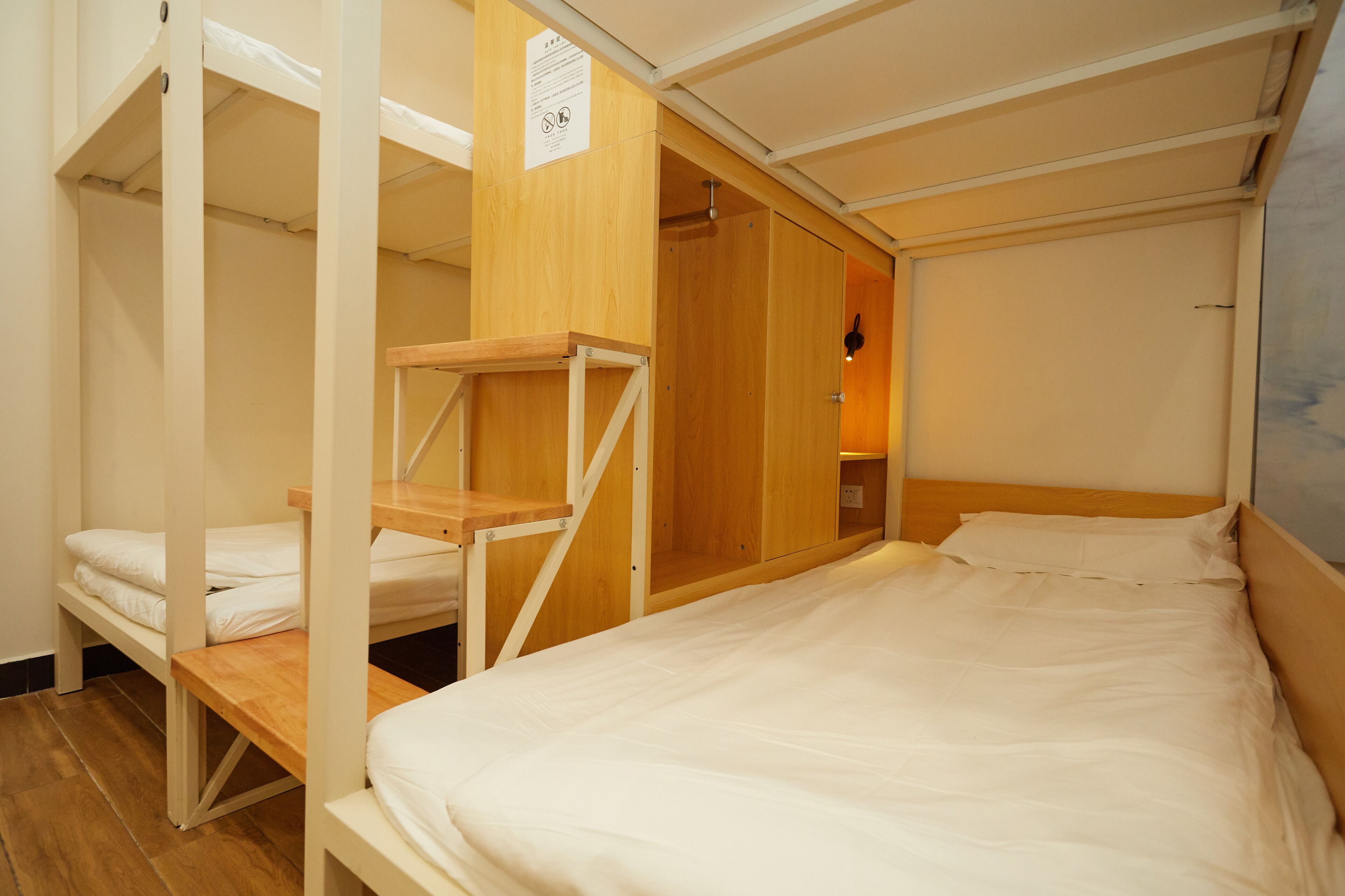 A bunk bed room with a wooden ladder, a wooden bench, and a wall-mounted shelf.