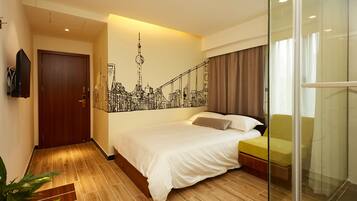 Une chambre d’hôtel avec un lit, une fresque représentant un paysage urbain, une cloison en verre et un plancher en bois.