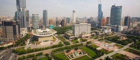 A cityscape with modern skyscrapers, a central roundabout, and surrounding green spaces.