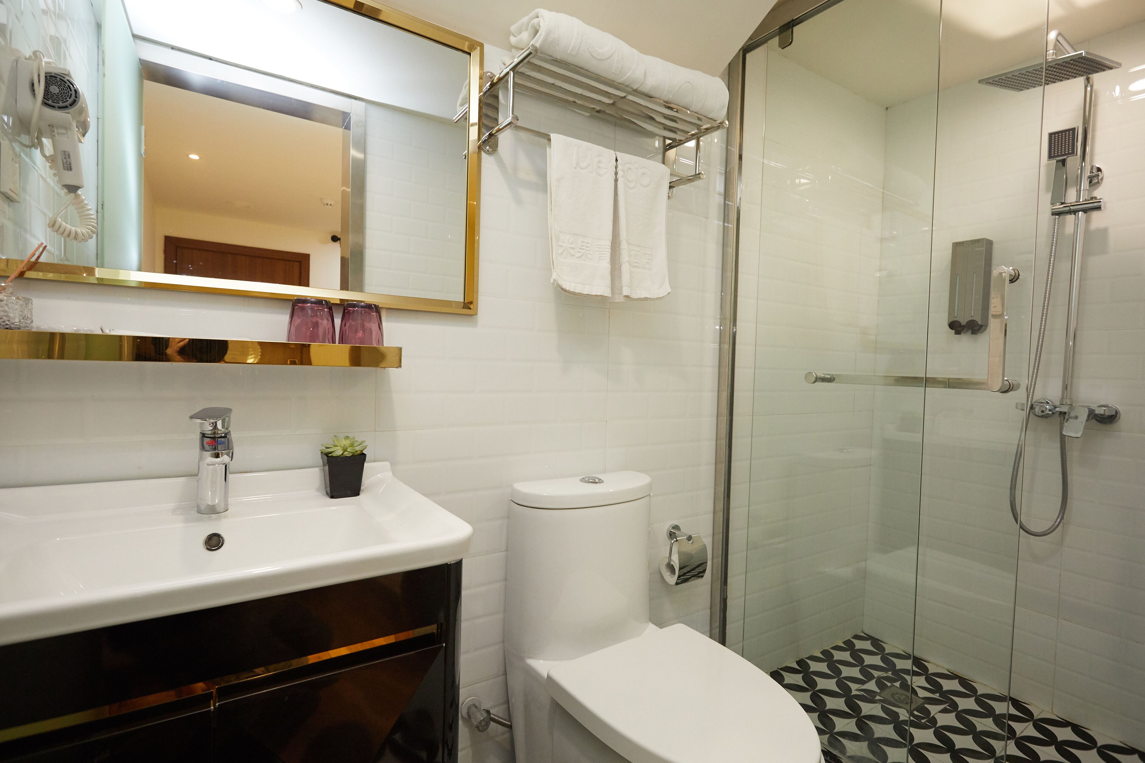 A bathroom with a white sink, a toilet, a glass-enclosed shower, and a mirror above the sink.