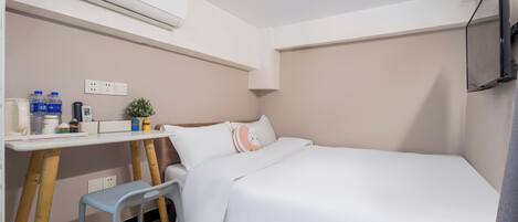 Una habitación pequeña y ordenada con cama, escritorio, silla, televisor y aire acondicionado.