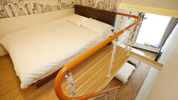 A bed with a wooden headboard, a metal railing, and a cityscape mural on the wall.