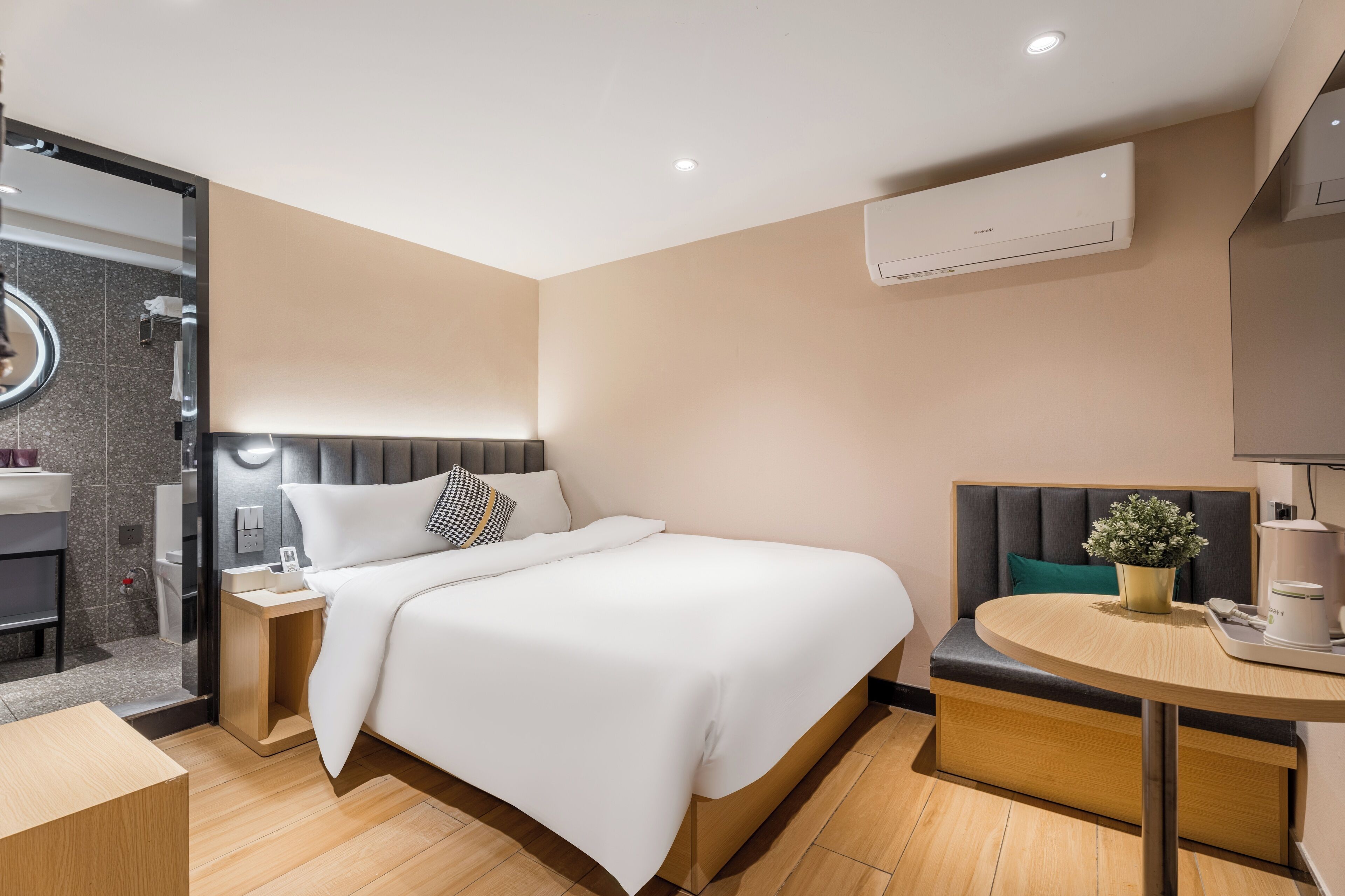 Una moderna camera d'albergo con un letto, un comodino e un tavolino rotondo con una macchina per il caffè.