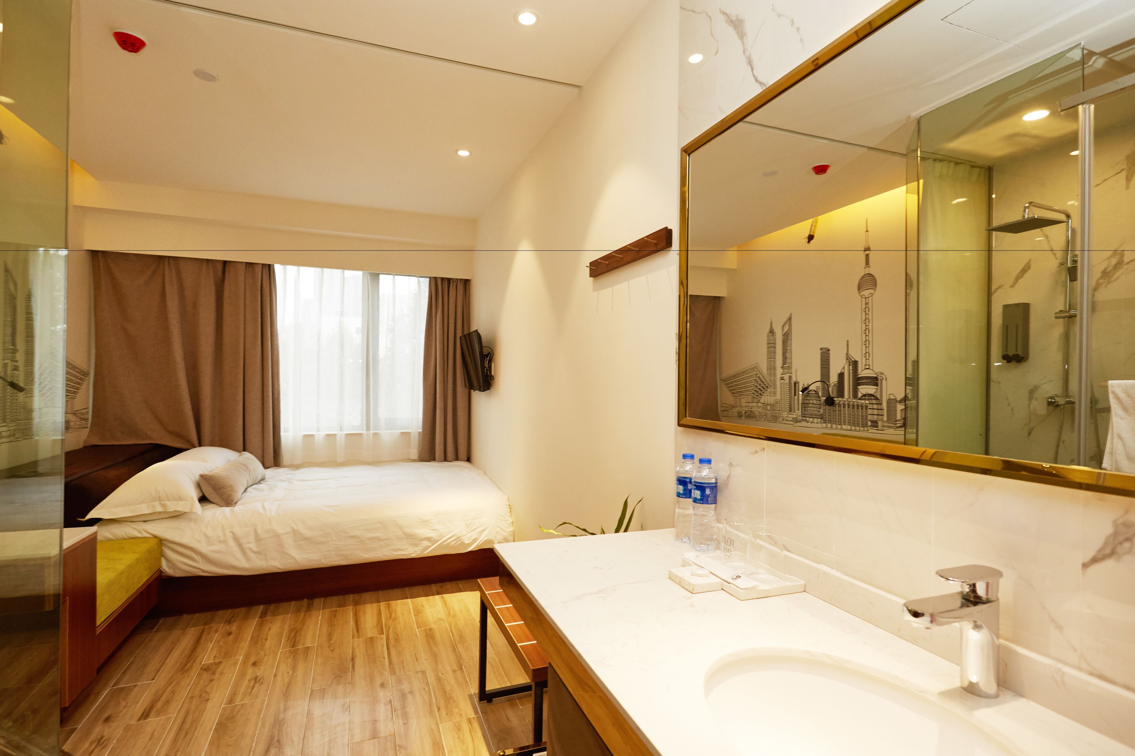 Een hotelkamer met een bed, een badkamer met een grote spiegel en uitzicht op de stad.