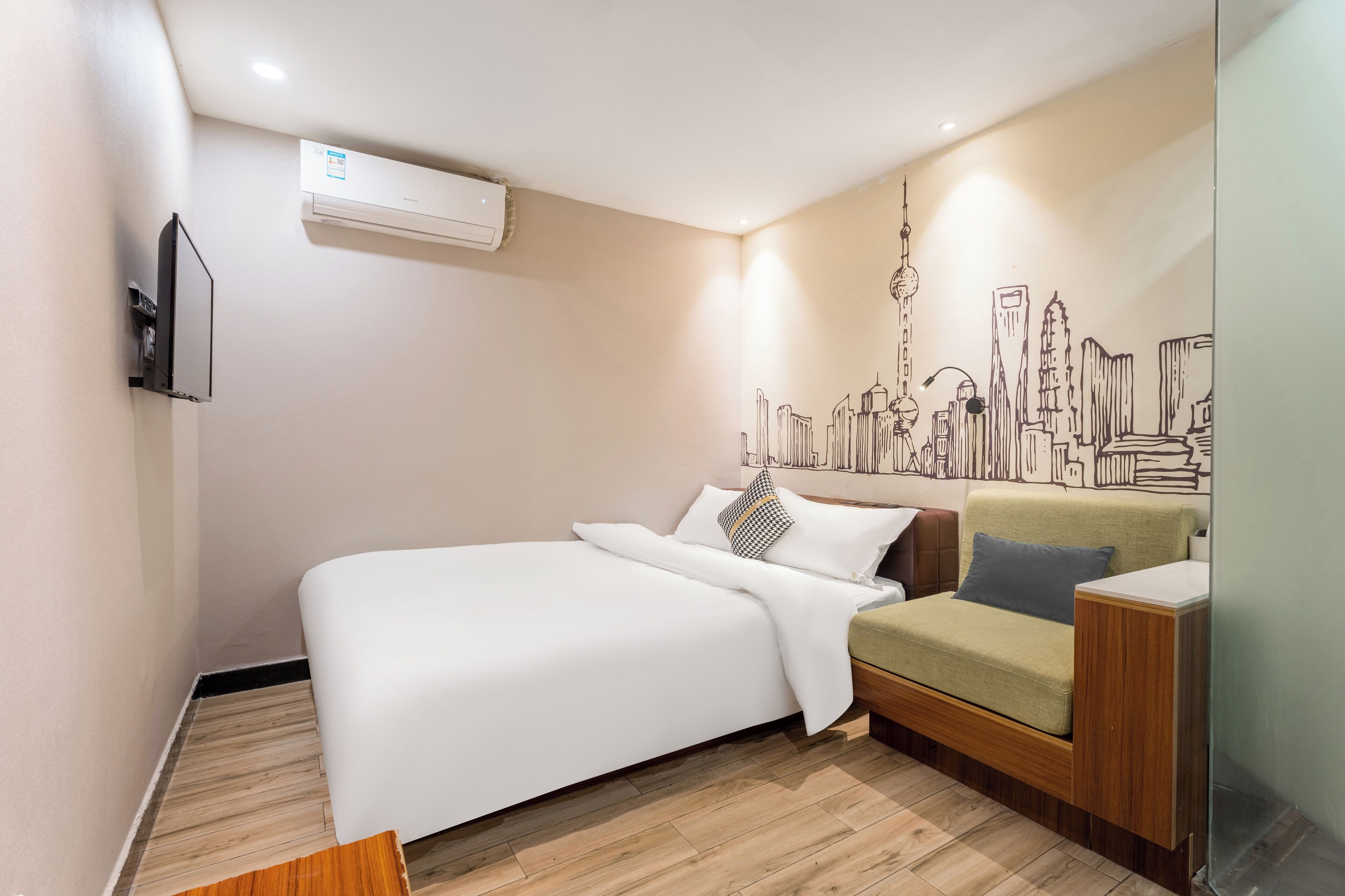 Una habitación de hotel moderna con una cama, un sofá, un mural con vista a la ciudad y un equipo de aire acondicionado.