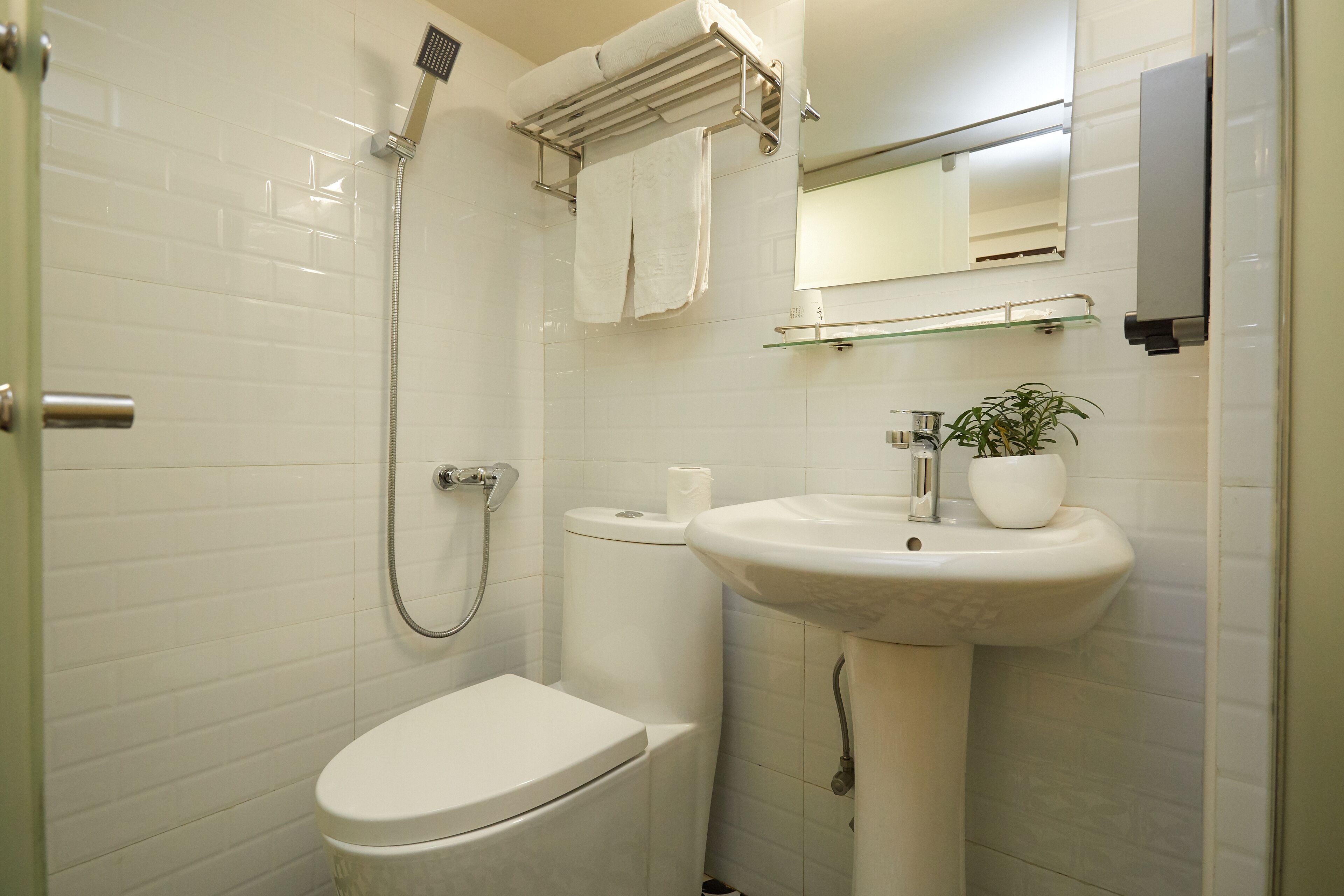 A bathroom with a toilet, sink, and shower.