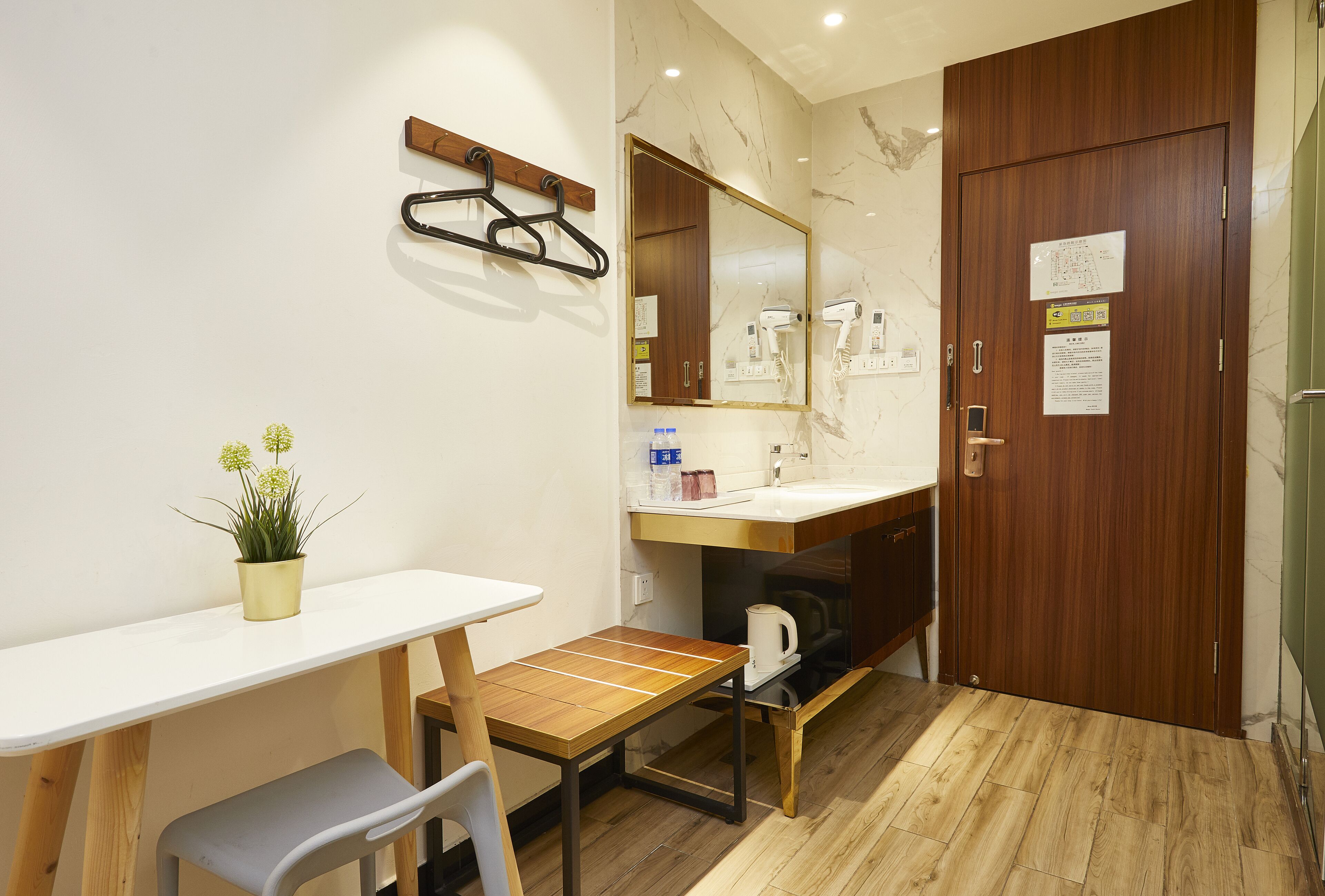Un baño de hotel con un tocador de madera, un espejo, un perchero para toallas, un lavabo y una pequeña mesa con una silla.