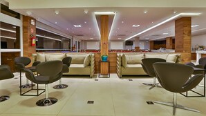 A spacious lobby with a central seating area, a fire extinguisher, and a large window. - Maringá Airport Hotel (Maringá)