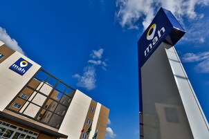 Um edifício moderno com um grande letreiro 'man', janelas amplas e um céu azul límpido.