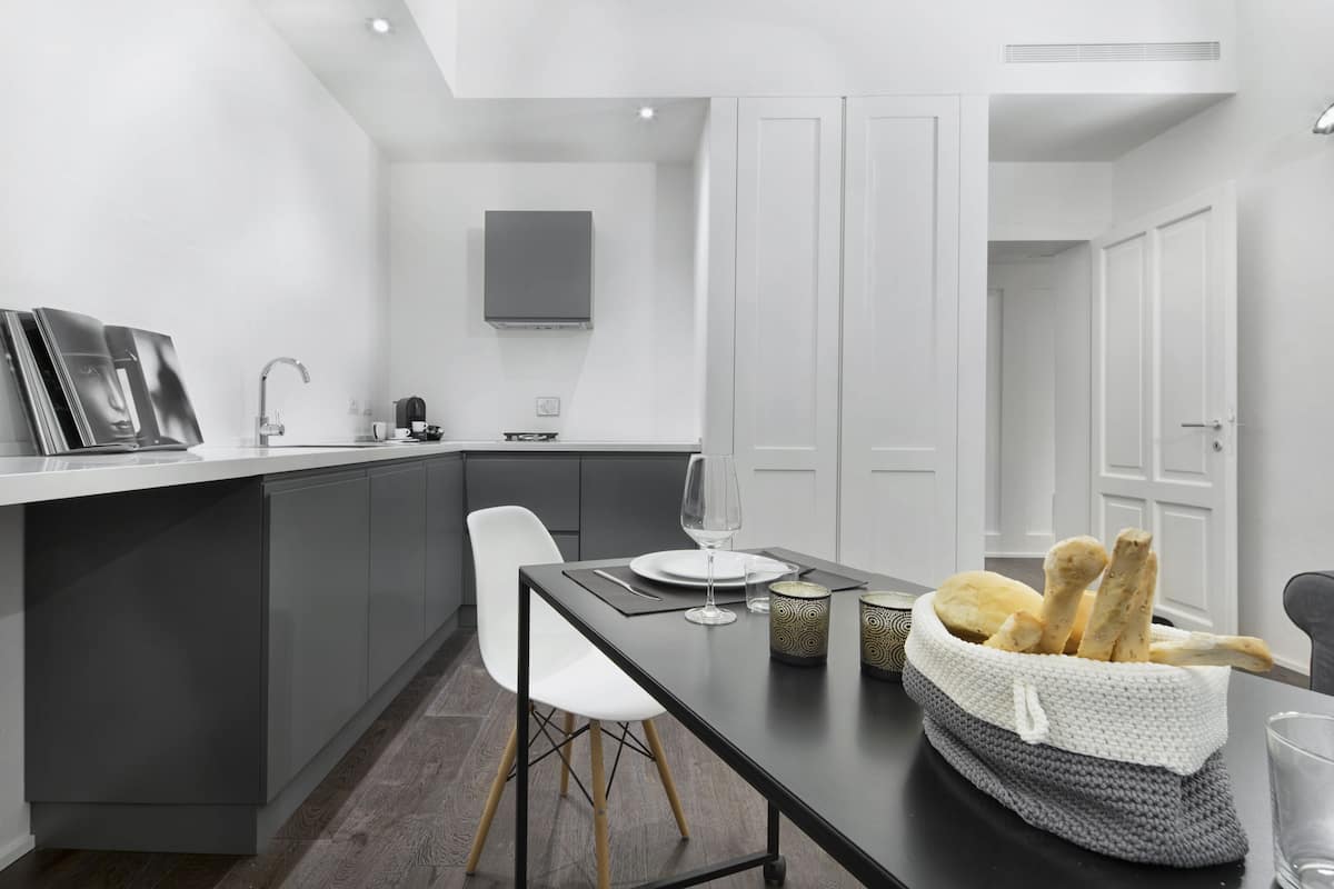 Una cocina moderna con una isla central, armarios blancos y encimera gris.