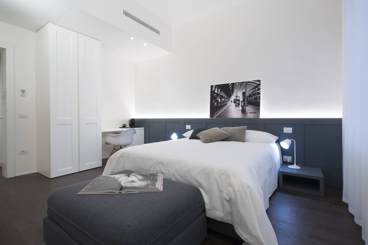 Un dormitorio moderno con una cama grande, mesitas de noche, un escritorio y un armario.