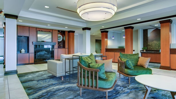 A spacious living area with a modern fireplace, comfortable seating, and a large chandelier. - Fairfield Inn & Suites by Marriott Decatur at Decatur Conference Center (Decatur)