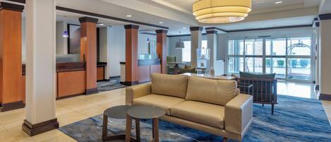A lobby with a beige sofa, two round tables, and a blue patterned carpet.