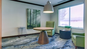 A room with a round table, a hanging light fixture, a painting, and two chairs. - Fairfield Inn & Suites by Marriott Decatur at Decatur Conference Center (Decatur)
