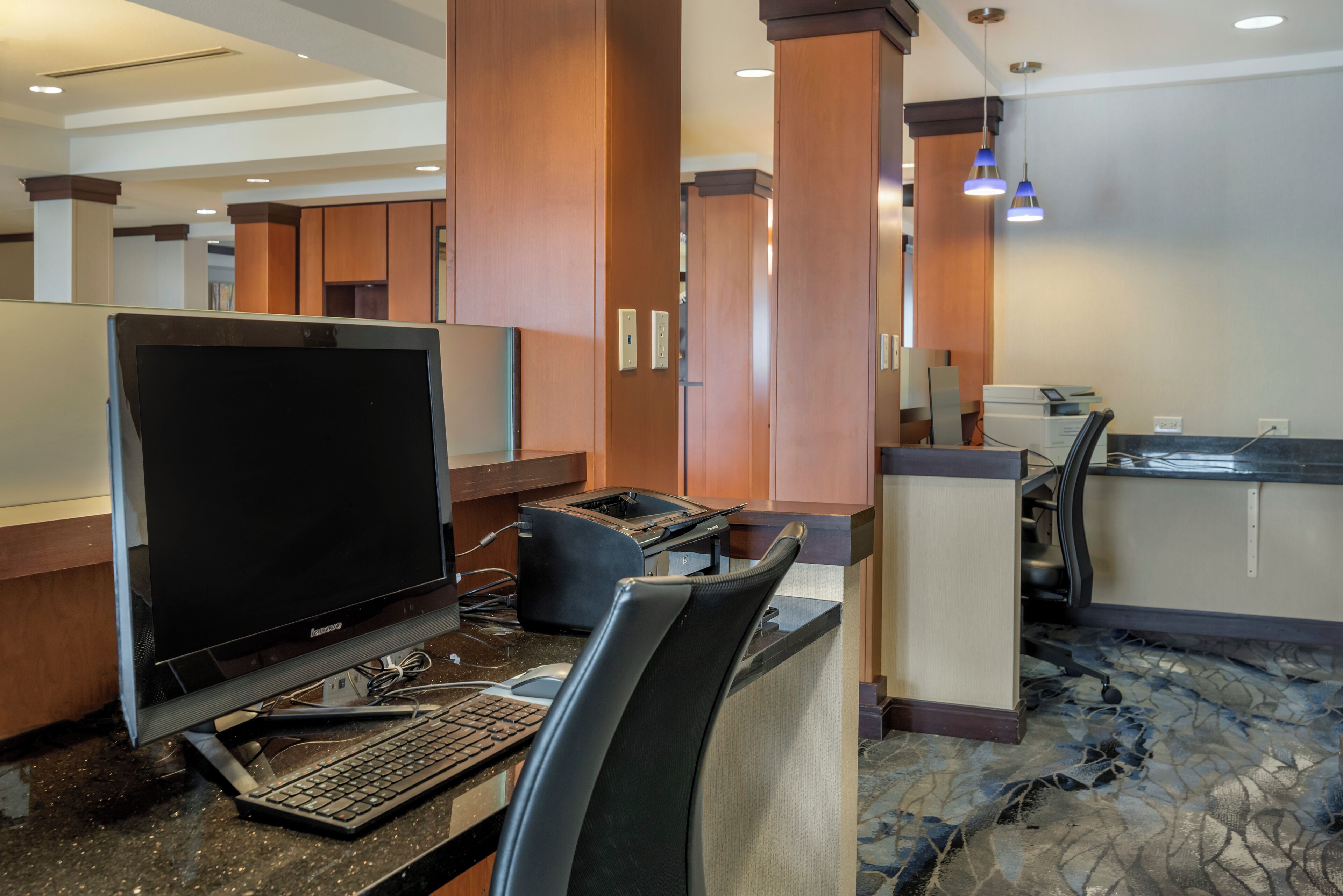 Un espace d’accueil d’hôtel comprenant un poste informatique, un téléphone et un comptoir.