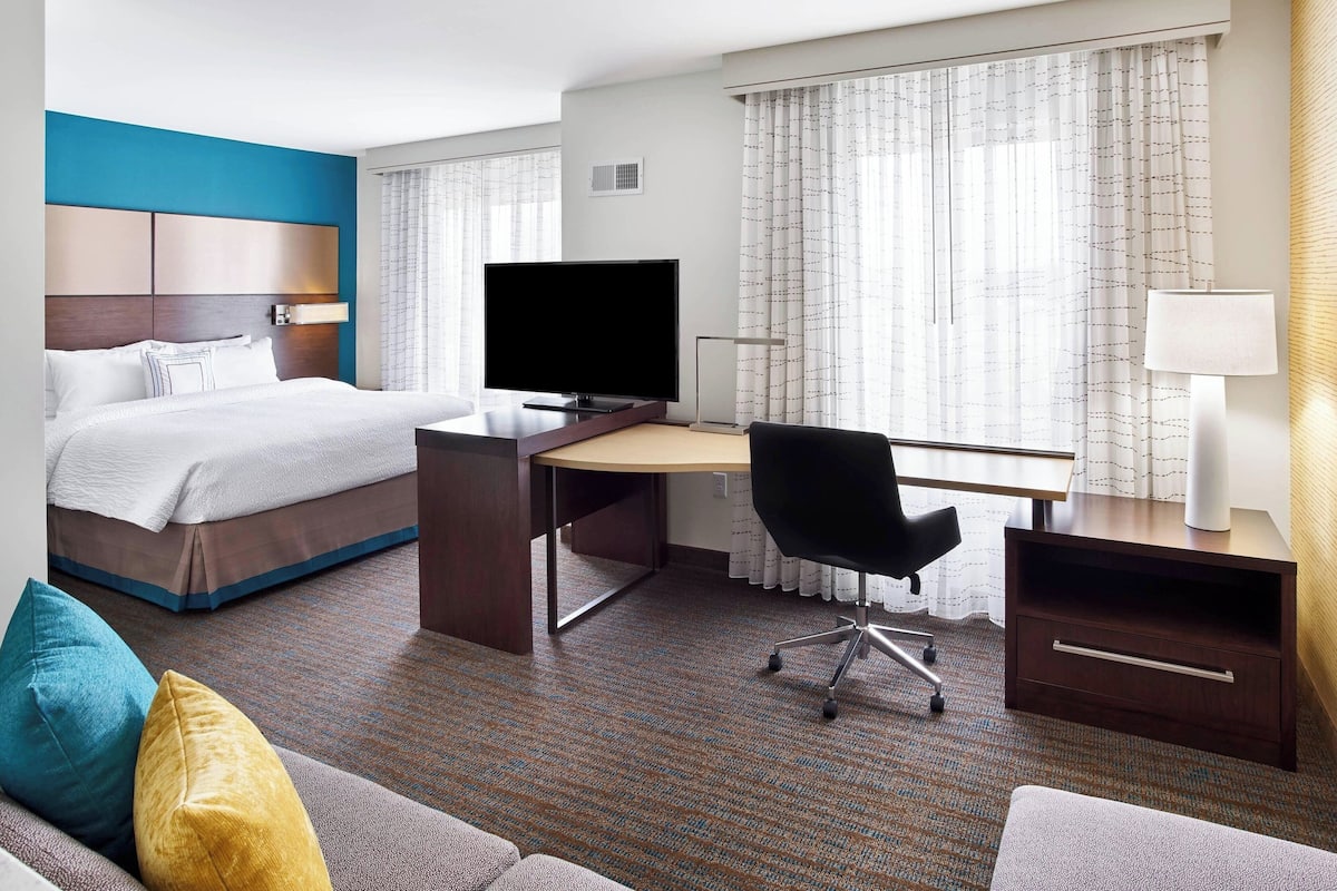 Une chambre d’hôtel équipée d’un lit, d’un bureau, d’une chaise, d’une télévision et d’une fenêtre avec des rideaux.