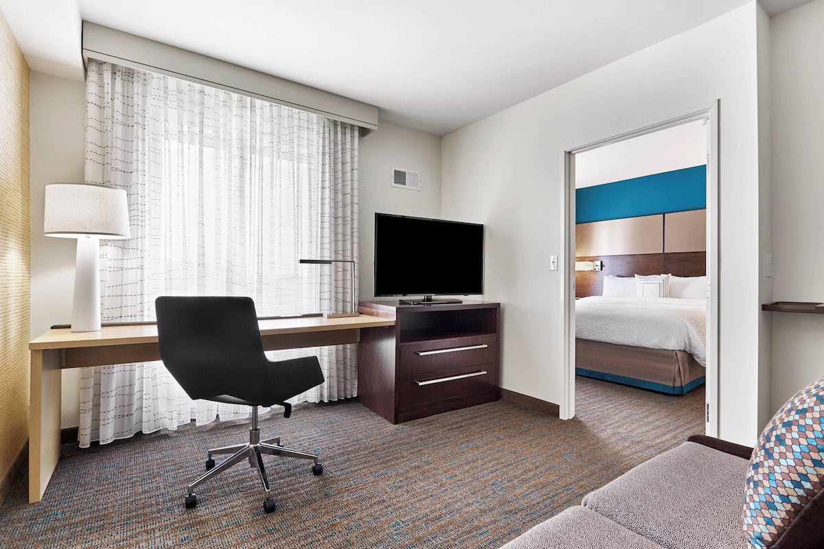 Une chambre d’hôtel équipée d’un bureau, d’une chaise, d’une télévision et d’un lit avec une tête de lit.