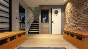 A modern interior with a wooden bench, a staircase, and a brick wall.