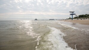 A beach with a lifeguard tower, a pier extending into the water, and a sandy shore.