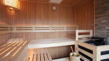 A sauna with wooden benches, a stone wall, and a wooden ceiling.