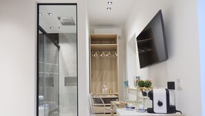Ein modernes Badezimmer mit einer Duschkabine aus Glas, einem Holzbadezimmer-Möbelstück mit Waschbecken und einem angebrachten Fernseher.