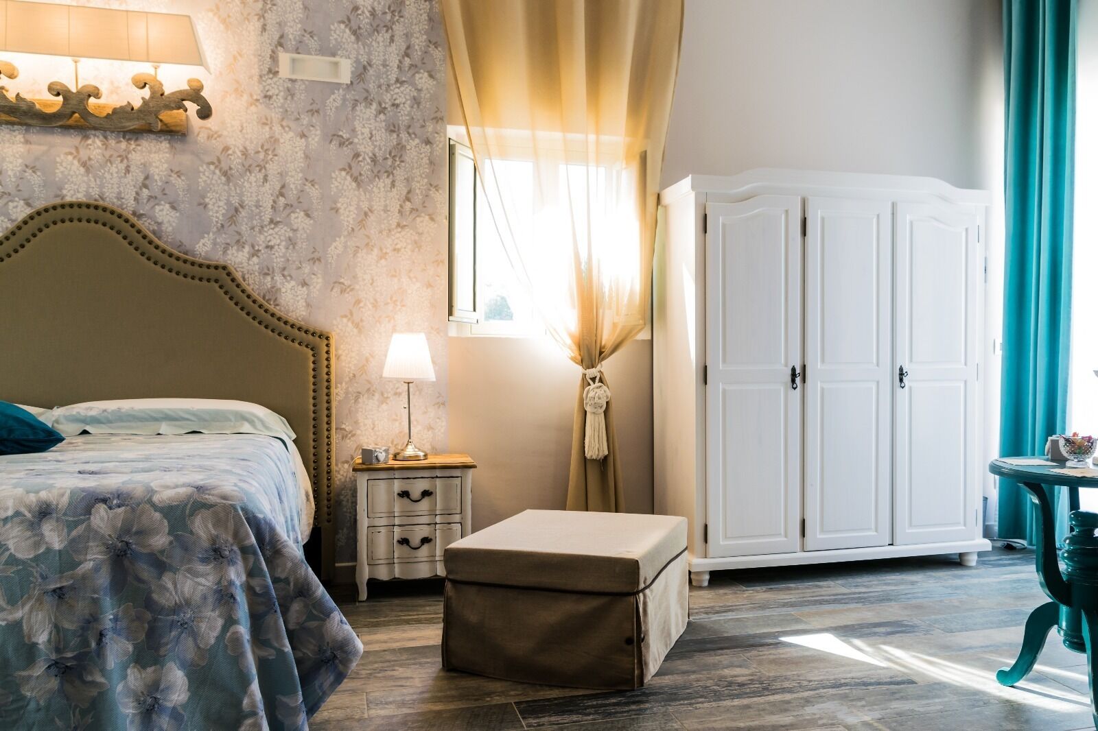 Una camera da letto con un letto, un comodino, una lampada, un armadio e un tavolino con una ciotola.