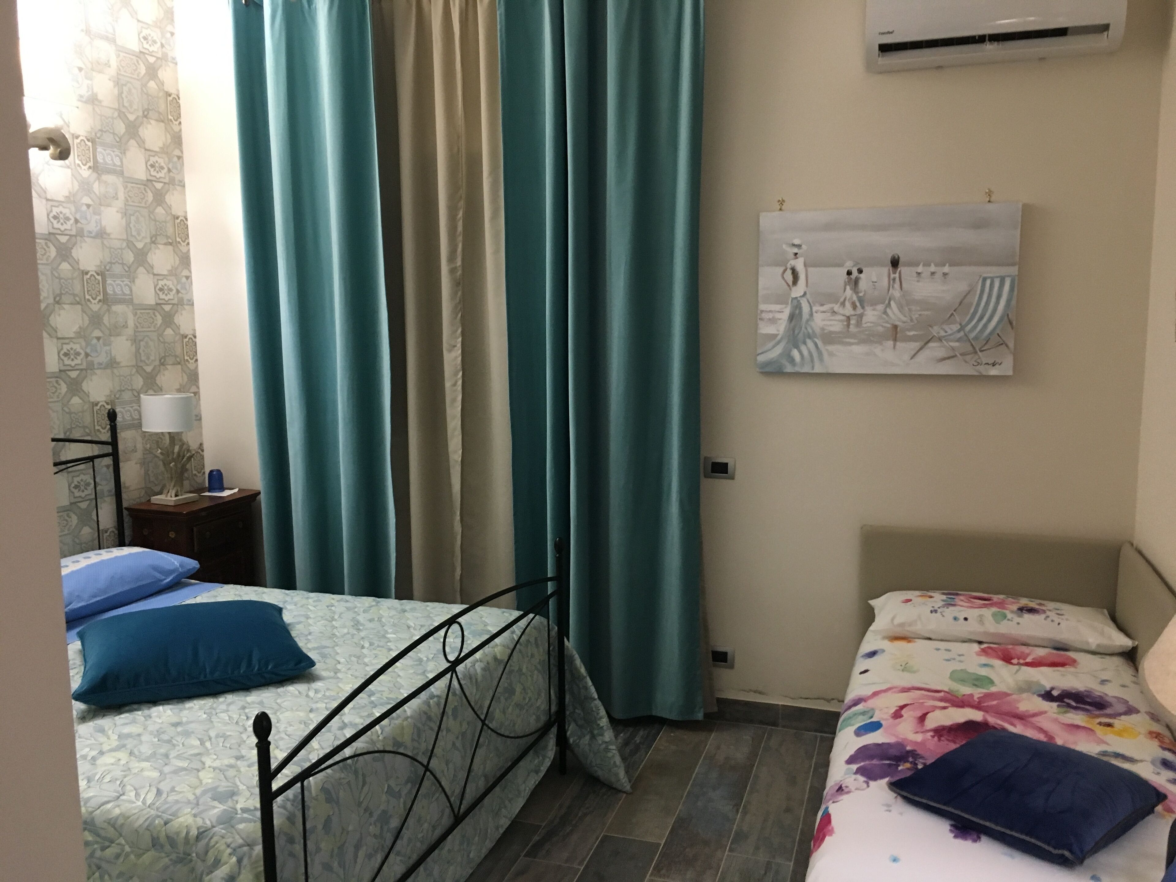 Une chambre avec deux lits, une table de chevet, une lampe et un tableau au mur.