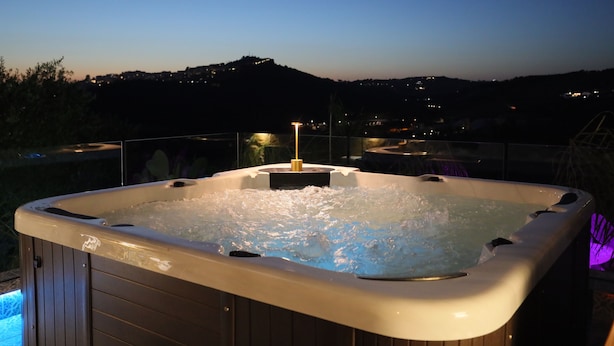Ein Whirlpool mit Blick auf eine Stadtlandschaft im Abendrot.