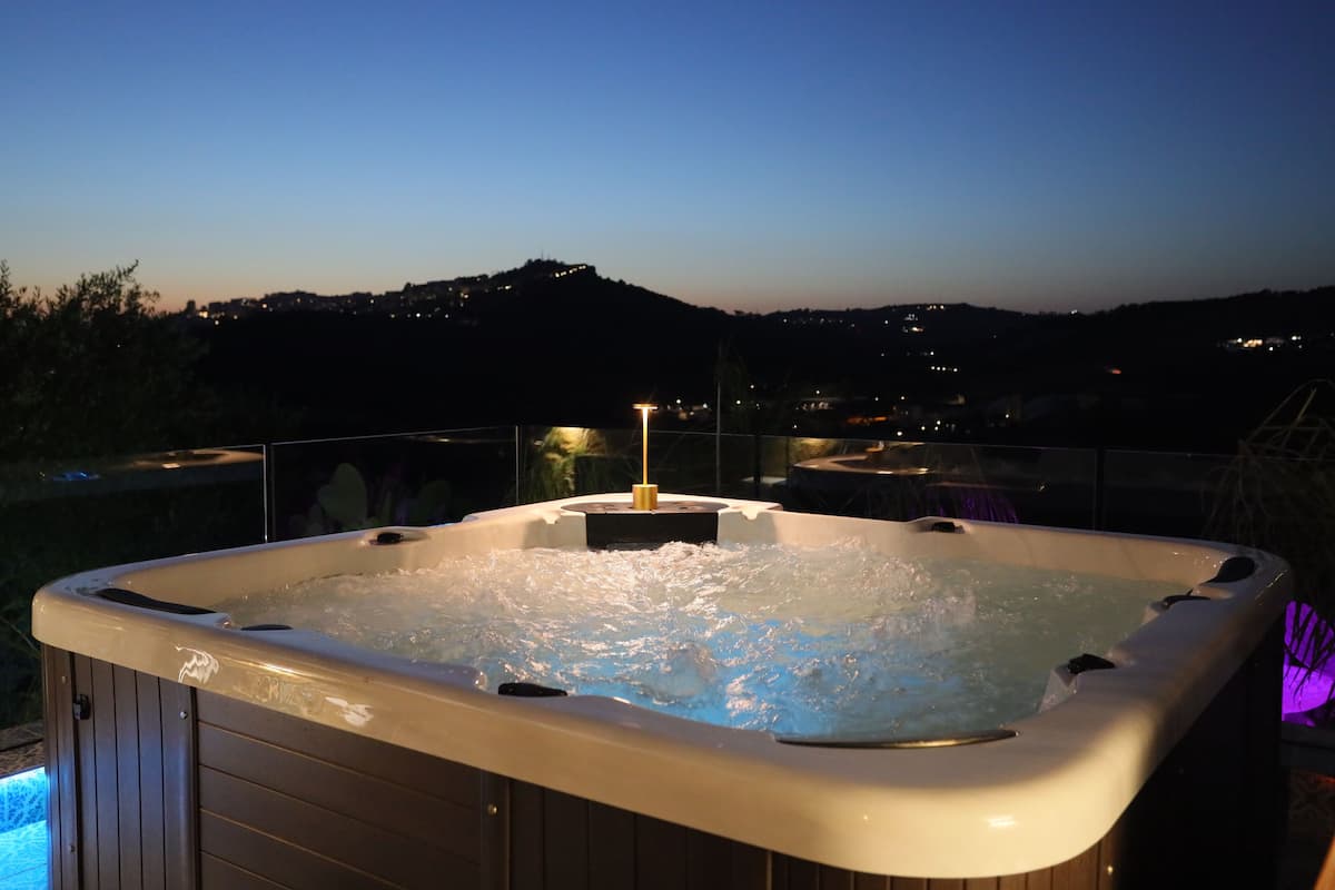 A hot tub with a view of a cityscape at dusk.