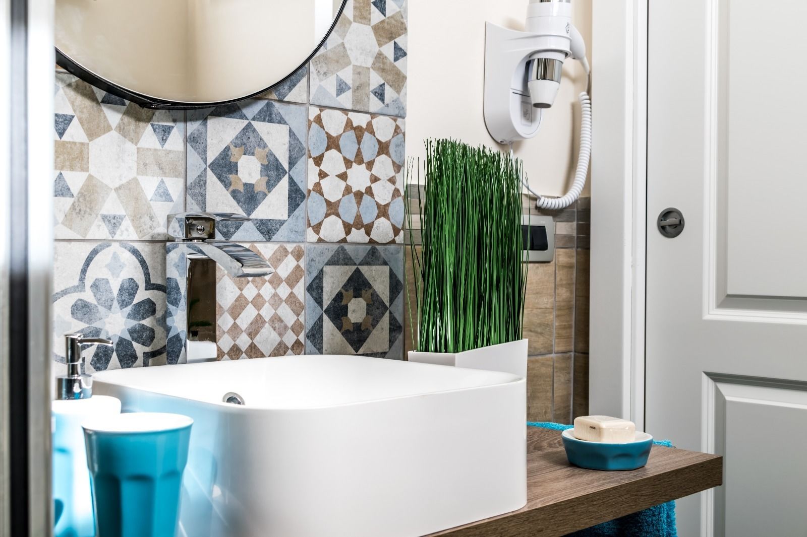 Een moderne badkamer met een vrijstaand bad, een beveiligingscamera aan de muur en een decoratieve tegelwand.