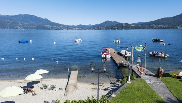 A lakeside view with boats, a dock, and a sign for 'Risto Bar'.