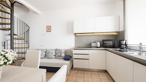 A compact kitchen with white cabinets, a built-in microwave, and a coffee maker.