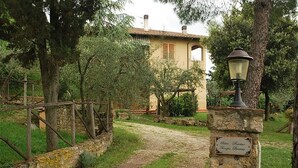 A rustic stone pathway leading to a traditional building with a tiled roof, surrounded by greenery and trees. - Lilla - Two Bedroom Apartment, Sleeps 6 (Poggibonsi)