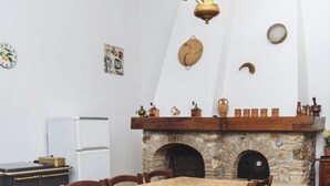 A dining area with a stone fireplace, a white refrigerator, and a table with chairs. - Lilla - Two Bedroom Apartment, Sleeps 6 (Poggibonsi)