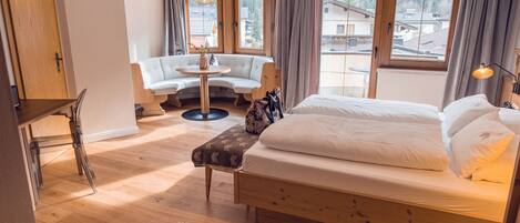 Un dormitorio con una cama de madera, una mesa redonda, un sofá y ventanas amplias.