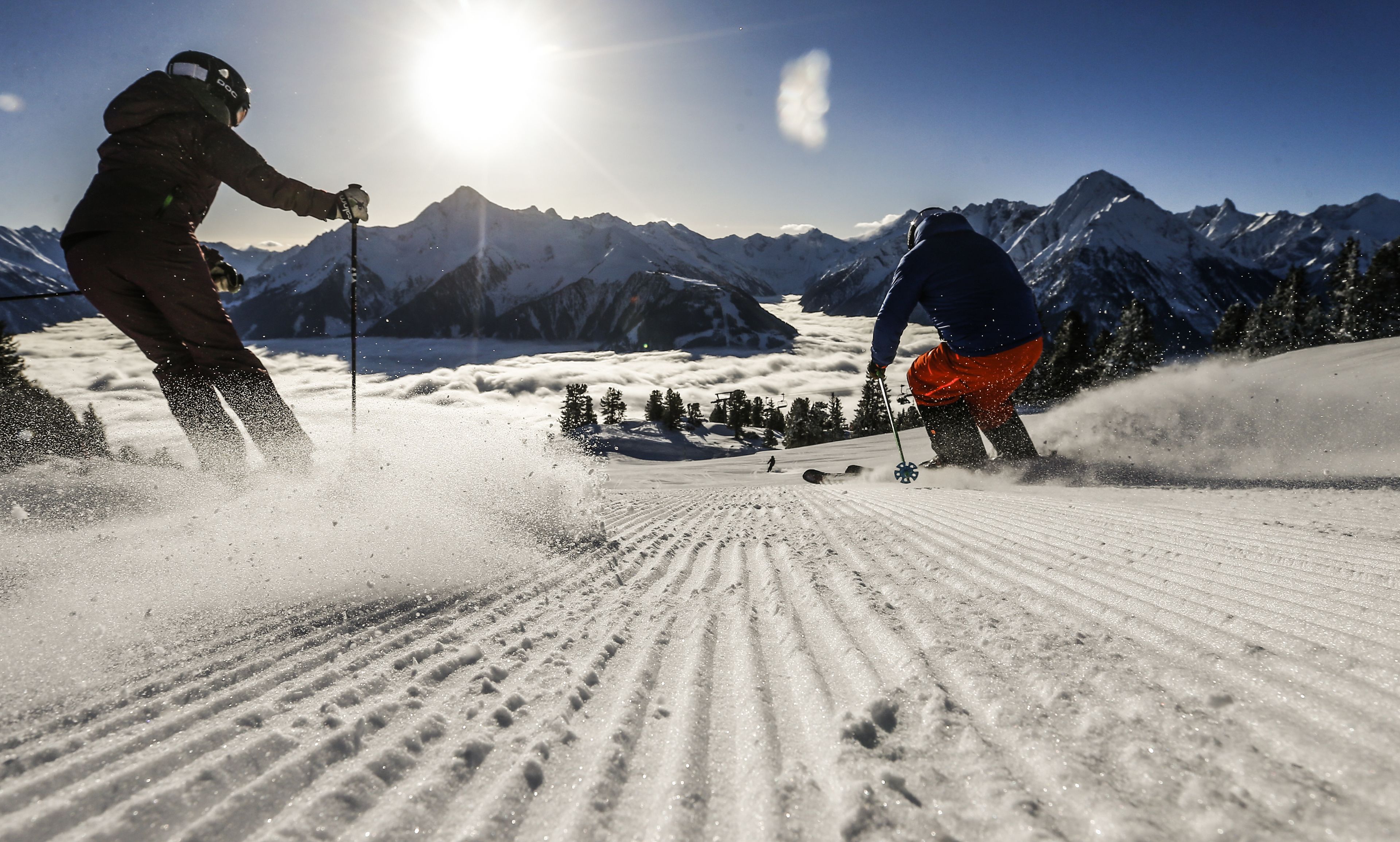 Ein verschneiter Skiabhang mit Skifahrern und einem Berg im Hintergrund.
