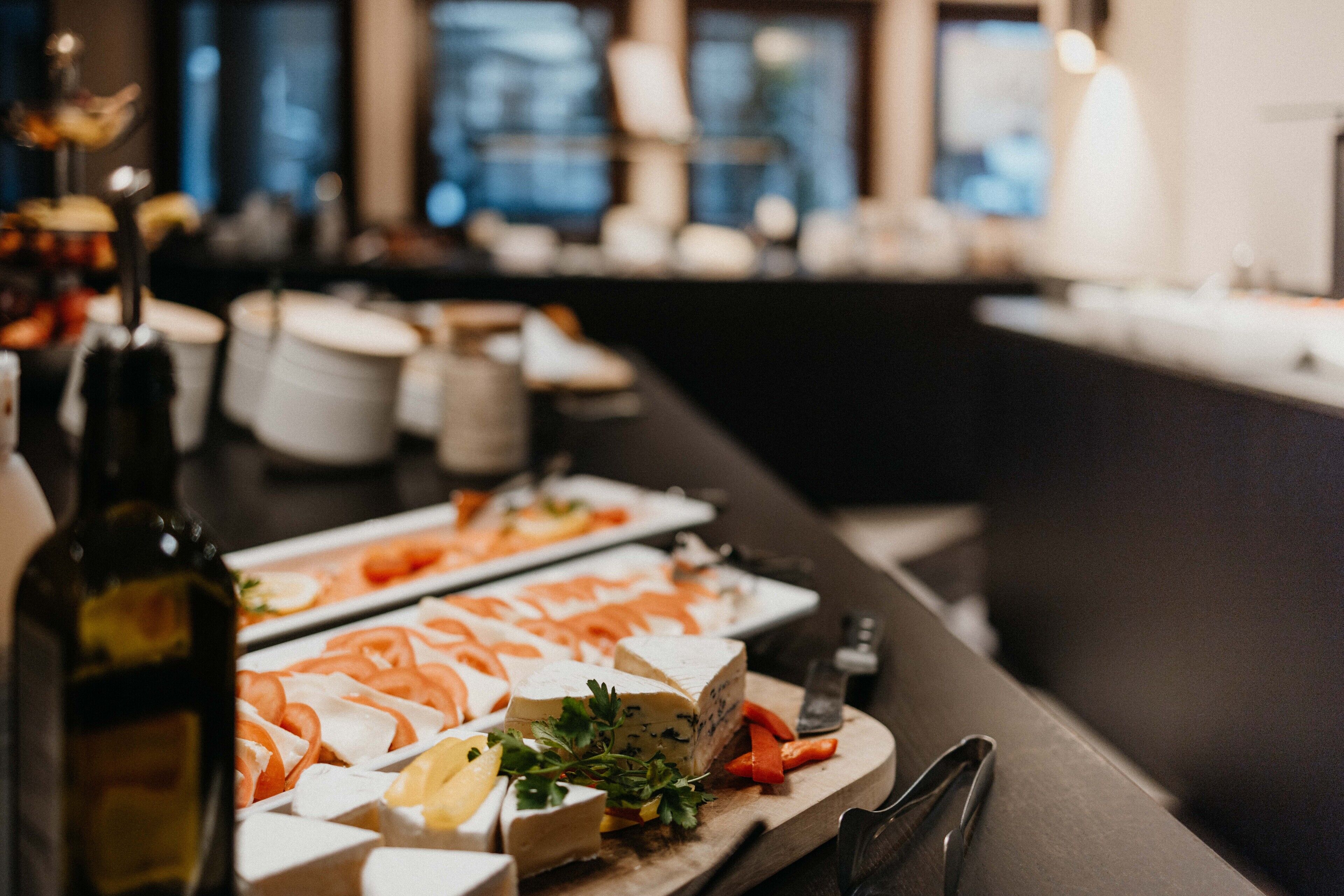 A buffet with various cheeses, fruits, and vegetables.
