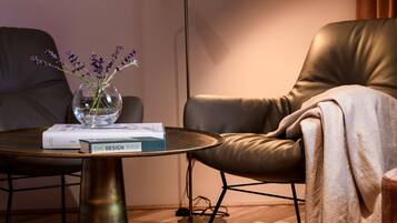 Un salon moderne avec une table basse ronde, un fauteuil en cuir, un lampadaire et un vase rempli de fleurs.