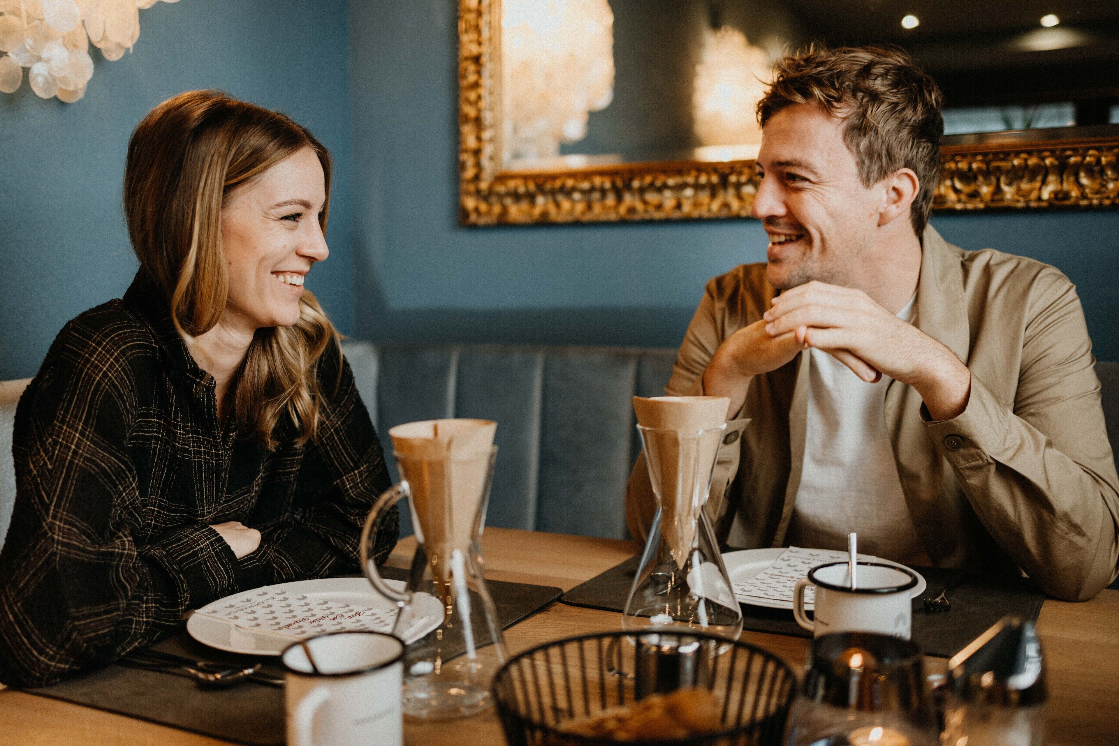 A couple dining at a restaurant with a blue wall and a framed picture in the background.