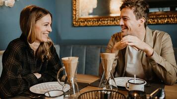 A couple dining at a restaurant with a blue wall and a framed picture in the background.