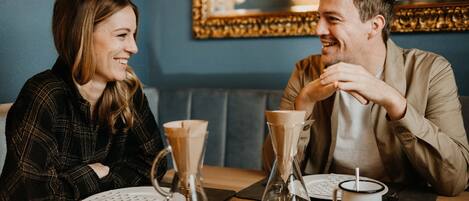 A couple dining at a restaurant with a blue wall and a framed picture in the background.