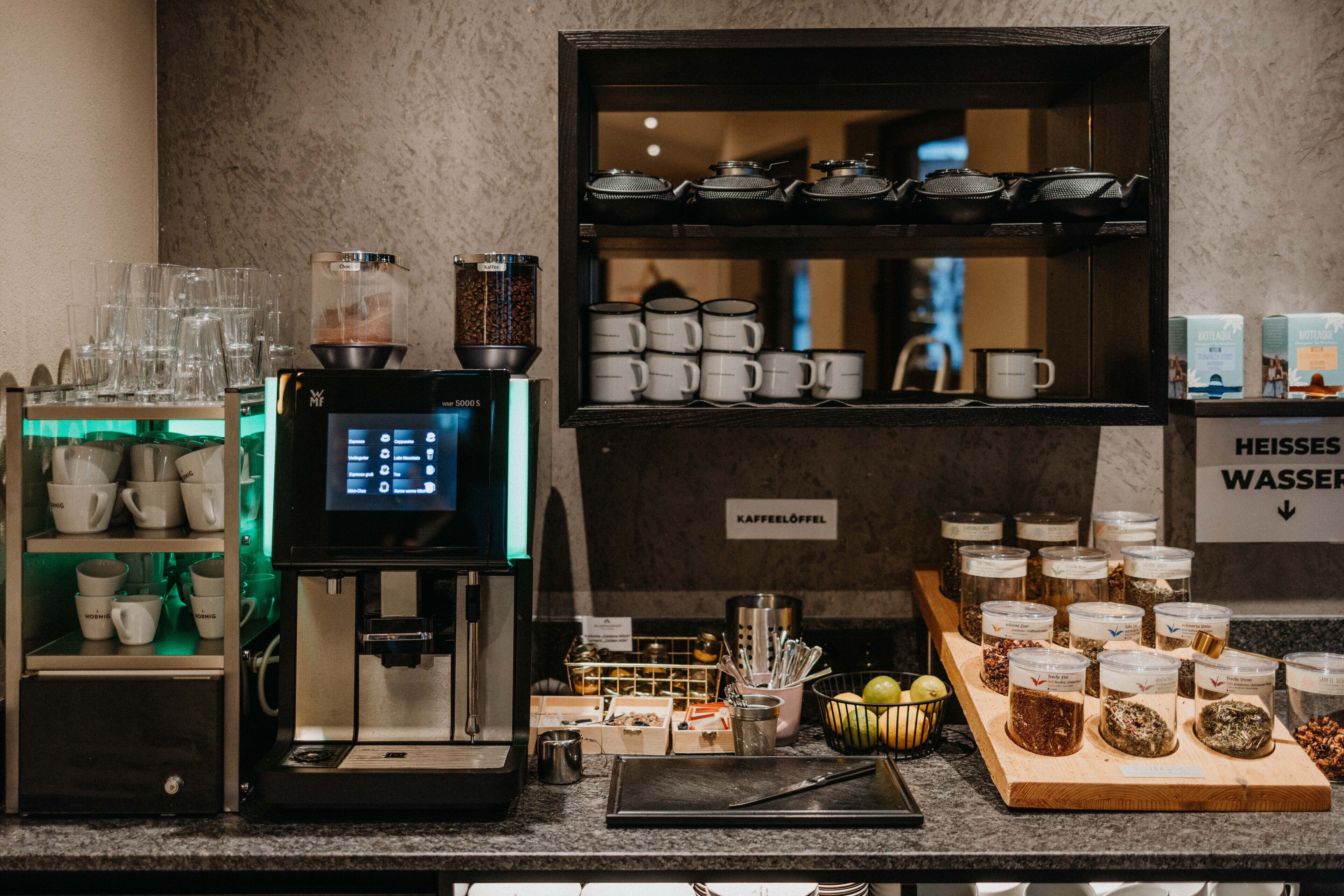 A coffee station with a coffee machine, cups, and various coffee beans.