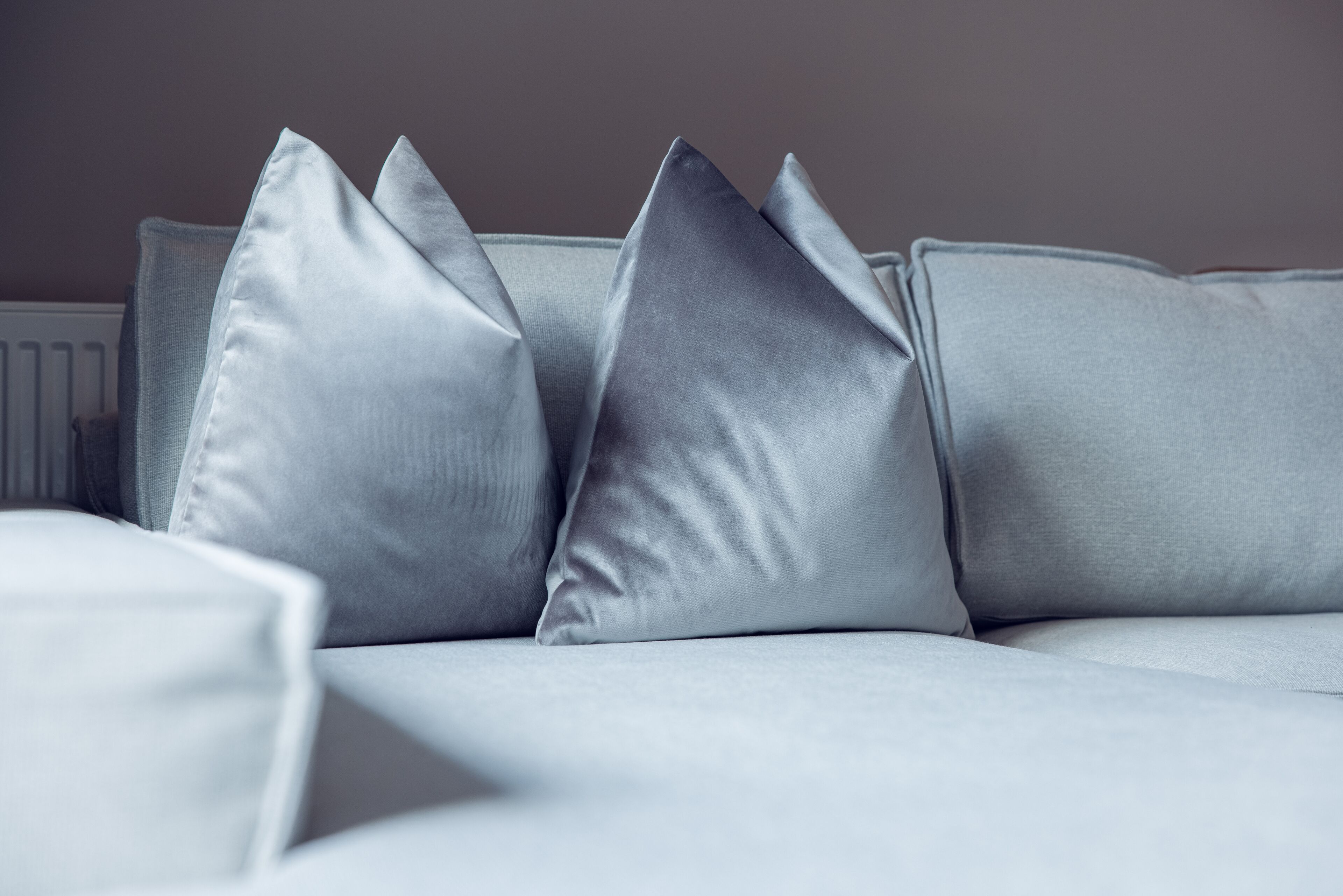 Ein graues Sofa mit drei Kissen.