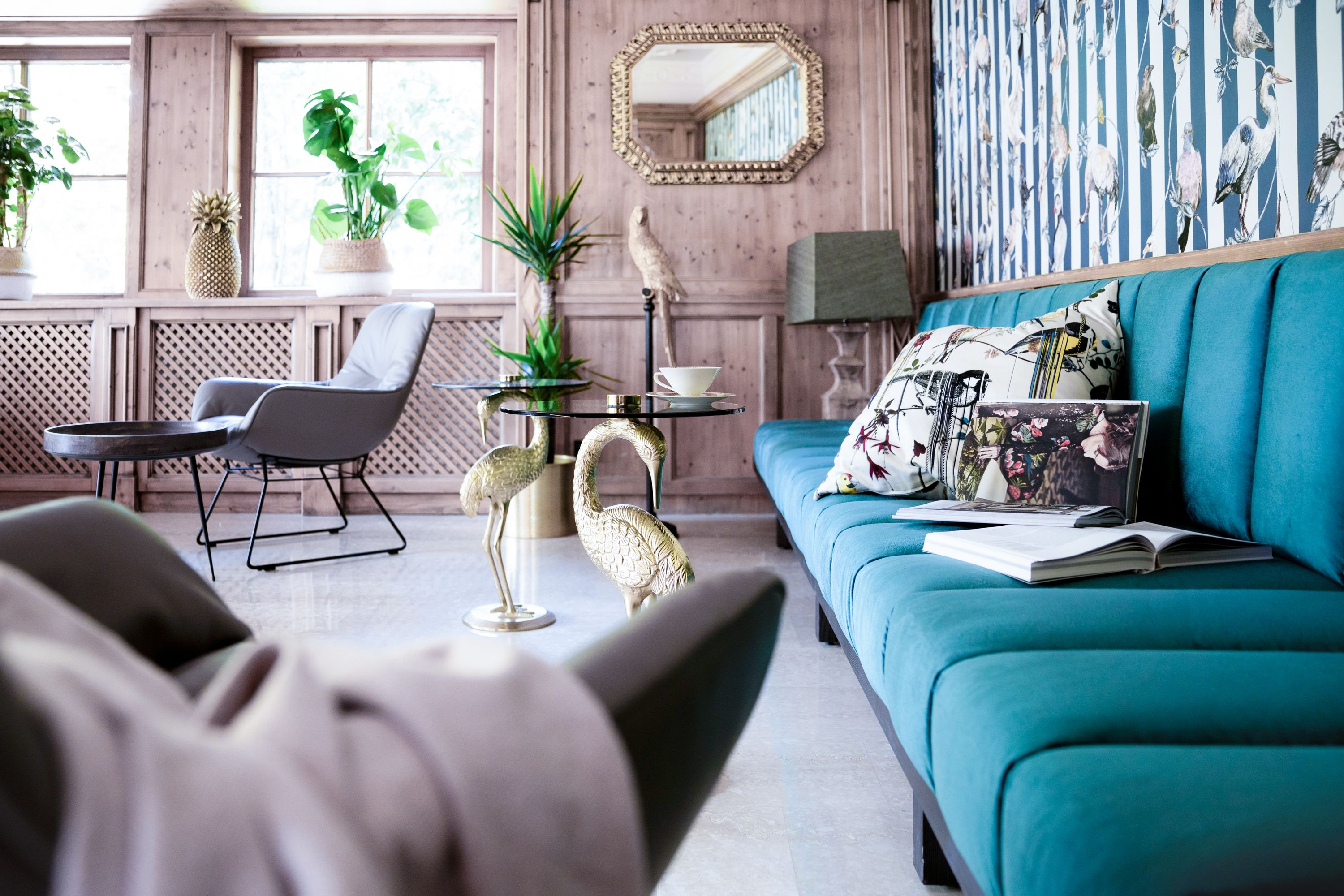 Un salon avec un canapé de couleur turquoise, une table basse et des objets décoratifs, notamment un ananas et une sculpture d’oiseau.