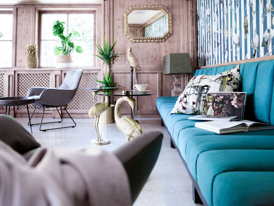 Un salon avec un canapé de couleur turquoise, une table basse et des objets décoratifs, notamment un ananas et une sculpture d’oiseau.