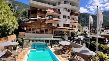 Relax by the pool with sun loungers and umbrellas, surrounded by trees and mountains.