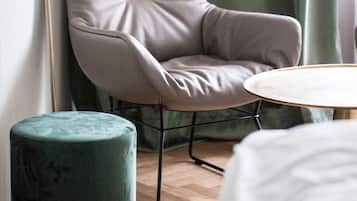 Una habitación moderna con un sillón tapizado de color gris, una mesa redonda y un otomano verde.