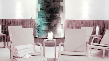 Un cuarto de spa con sillas de mimbre, un pilar central y una lámpara fijada a la pared.